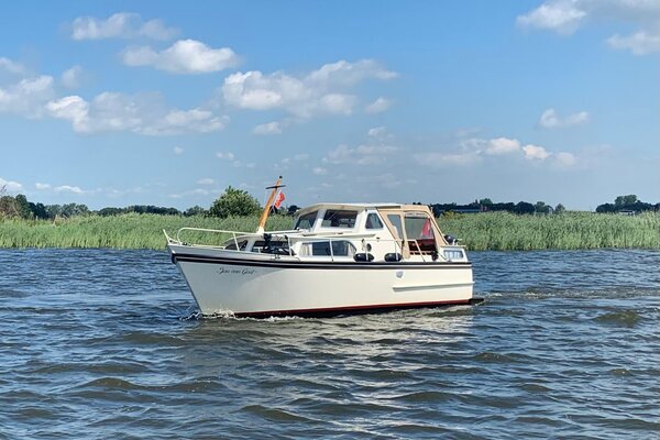 Motorboat on a boating holiday in Friesland, with reeds in the background. 